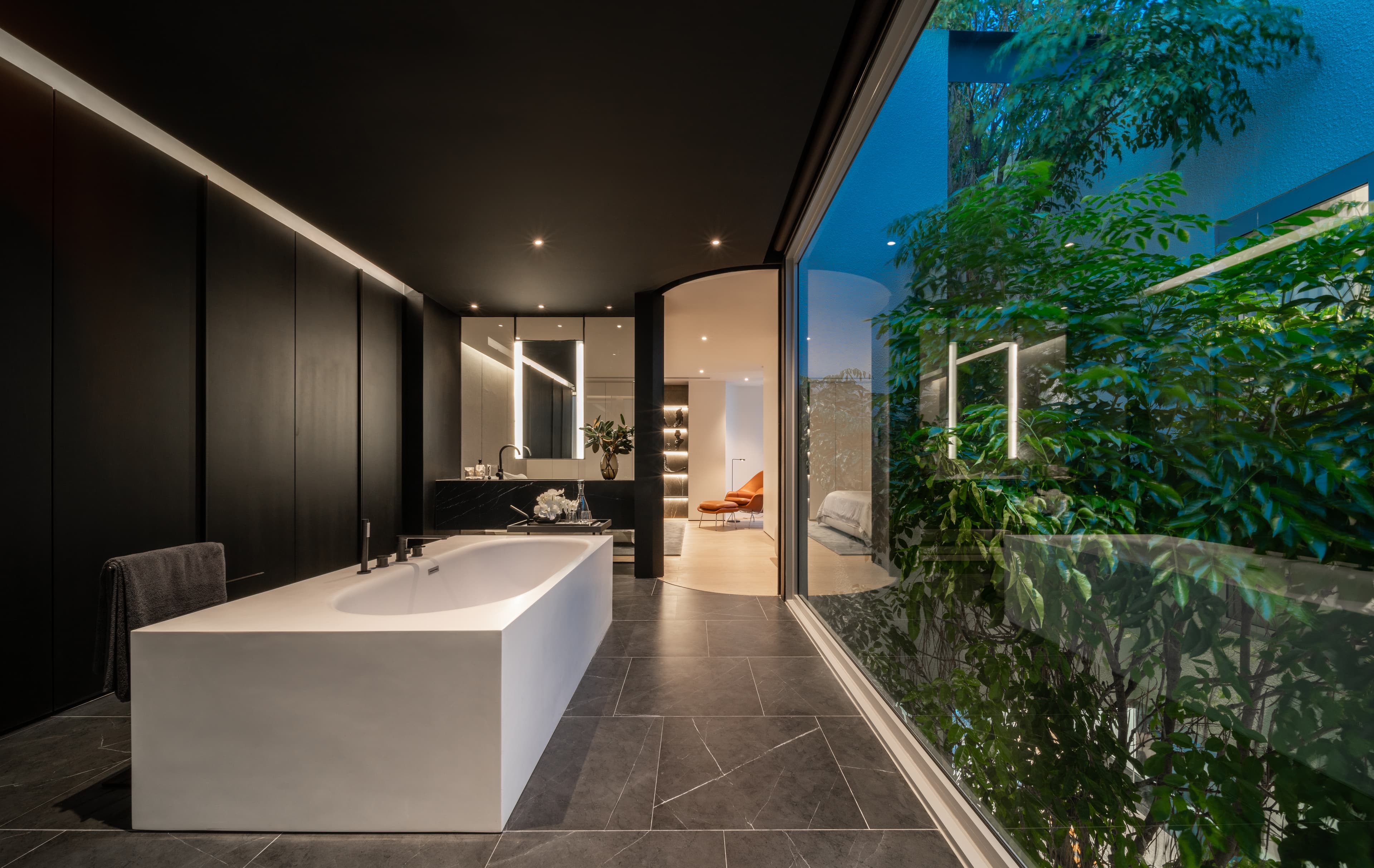 ARQ10 interior — dark bathroom opening to a courtyard garden