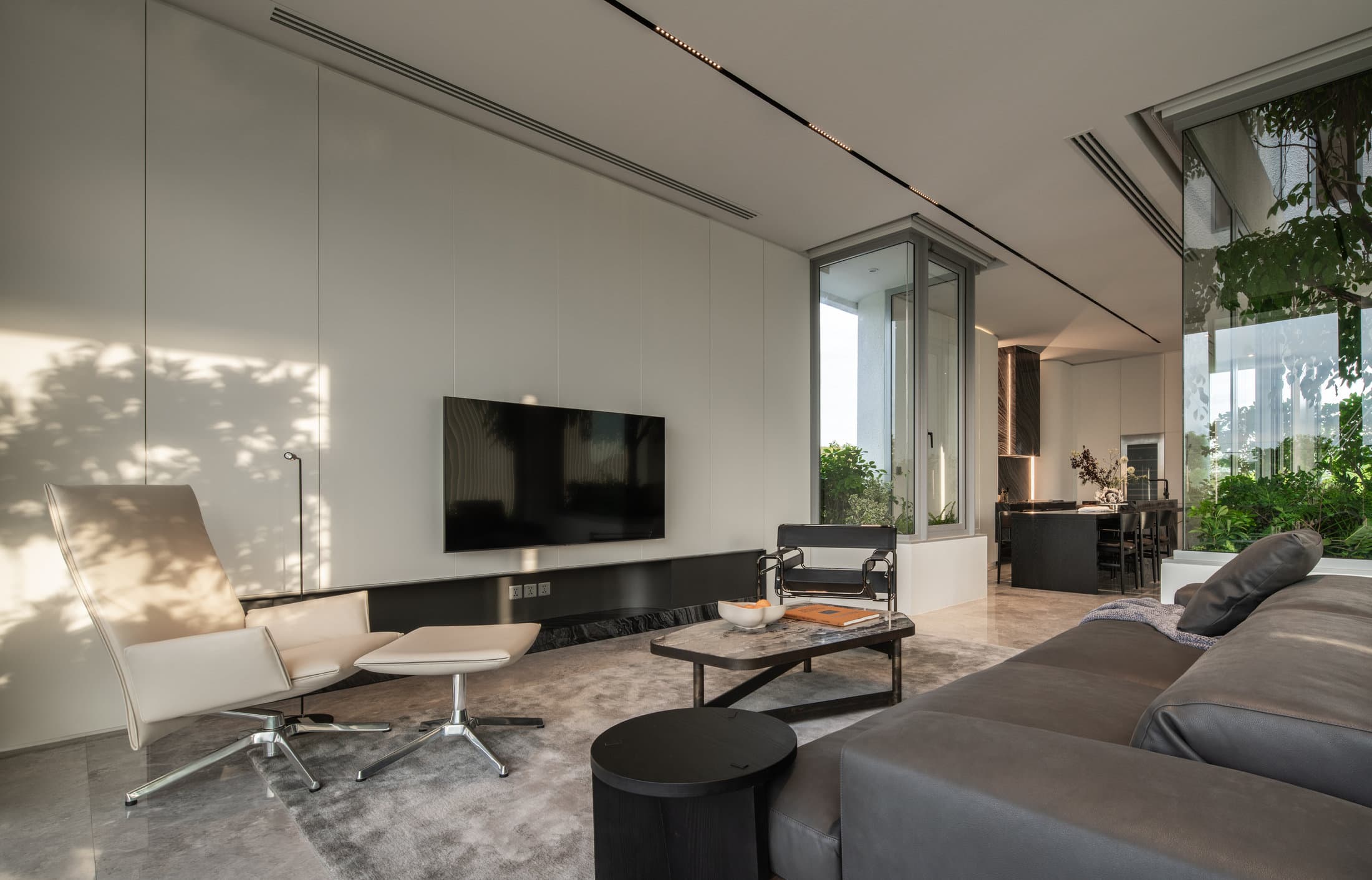ห้องนั่งเล่นสำหรับครอบครัวของ ARQ10 L-House ที่เปิดรับสวนภายใน